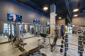A gym with a variety of equipment including treadmills, weights, and benches.